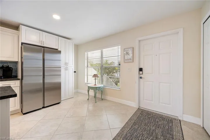 Kitchen featuring freestanding refrigerator, white cabinets, recessed lighting, dark stone countertops, and light tile patterned flooring