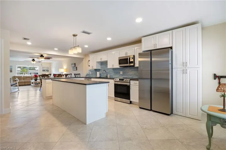 Kitchen with appliances with stainless steel finishes, decorative light fixtures, open floor plan, recessed lighting, and a kitchen island