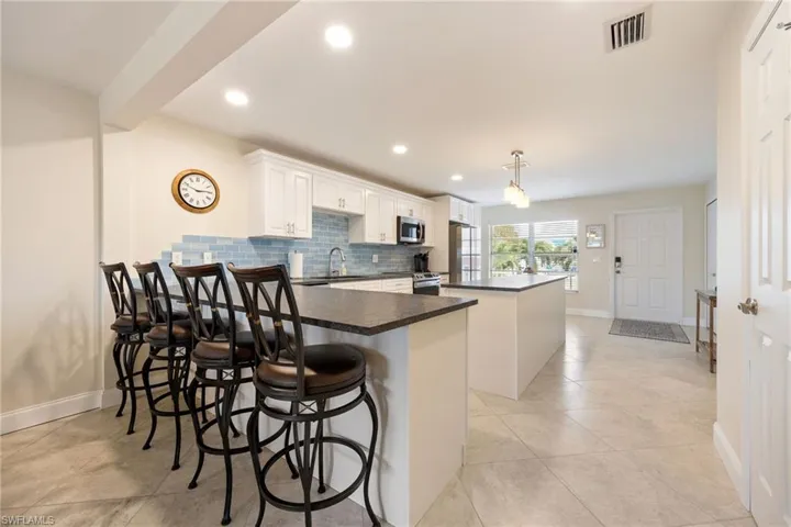 Kitchen featuring a kitchen island, recessed lighting, backsplash, white cabinets, and stainless steel appliances