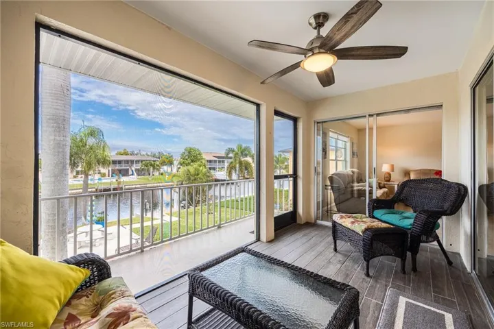 Sunroom featuring a water view, a ceiling fan, and a balcony