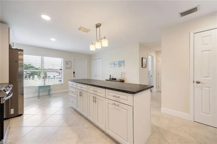 Kitchen with a kitchen island, white cabinets, decorative light fixtures, stainless steel appliances, and recessed lighting