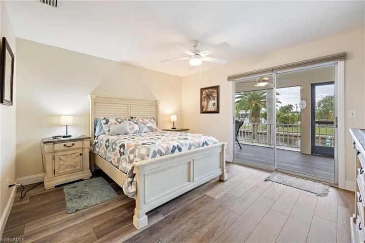 Bedroom featuring a water view, wood finished floors, access to outside, and ceiling fan