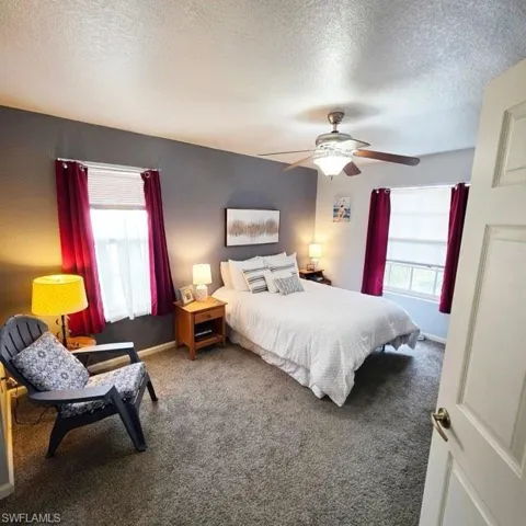 Bedroom with carpet floors, a ceiling fan, and a textured ceiling