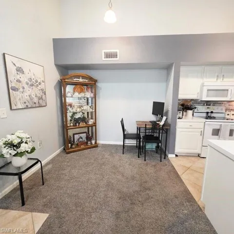 Dining room with light tile patterned floors, light colored carpet, and a desk
