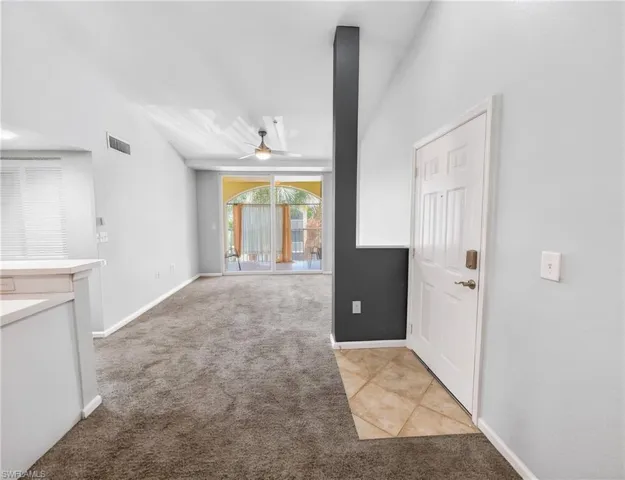 Living area featuring vaulted ceilings, a ceiling fan, plush gray carpeting, and sliding glass doors opening to an outdoor space