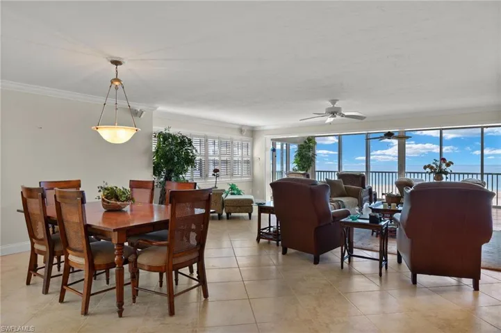 Dining area featuring a water view, ceiling fan, light tile patterned flooring, and crown molding