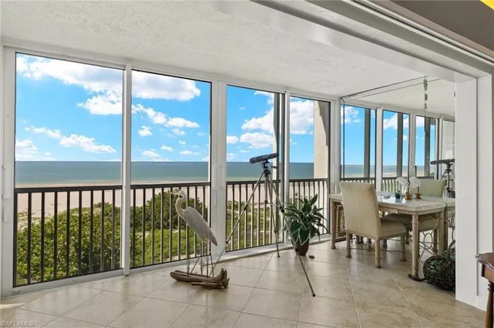 Unfurnished sunroom with a view of the beach, a water view, and a healthy amount of sunlight
