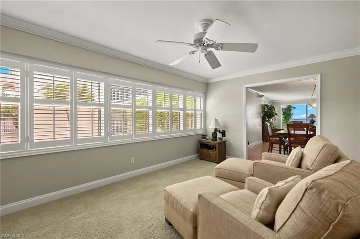 Living room featuring a healthy amount of sunlight, ornamental molding, light carpet, and ceiling fan
