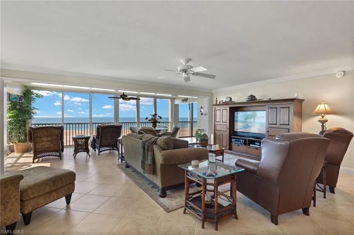 Tiled living room with a water view, ceiling fan, and crown molding