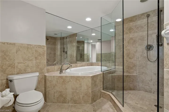 Bathroom featuring separate shower and tub, tile walls, tile patterned flooring, and toilet