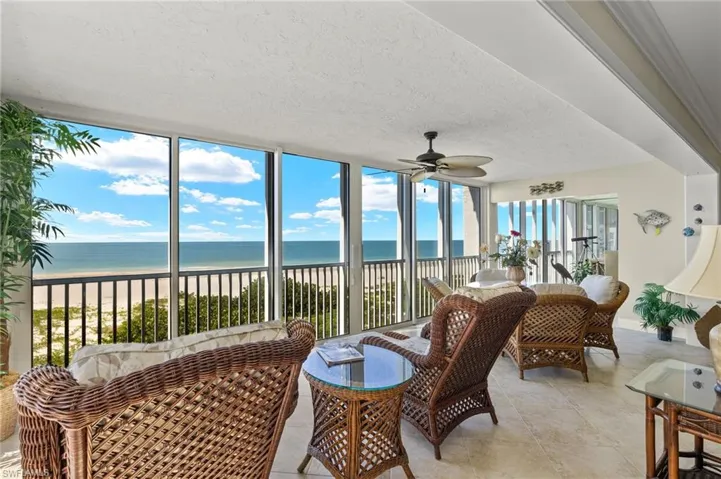 Sunroom featuring a view of the beach, a water view, ceiling fan, and plenty of natural light