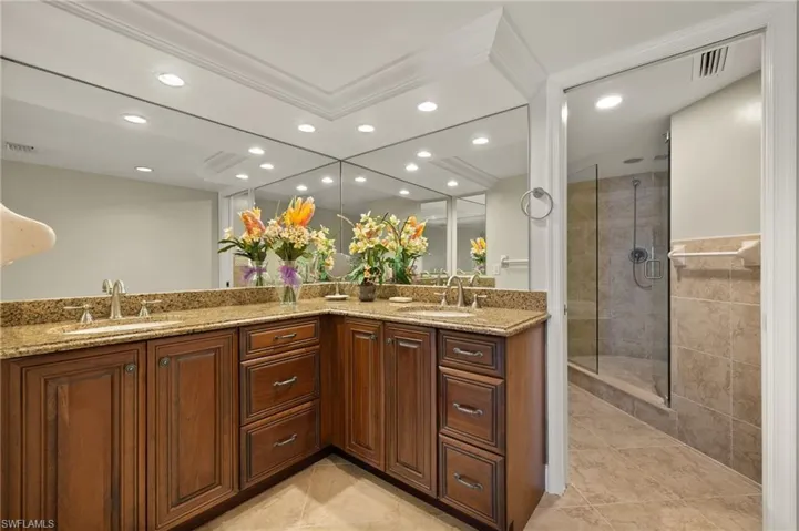 Bathroom with vanity, crown molding, tile patterned flooring, and a shower with door