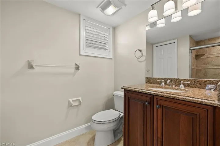 Bathroom featuring tile patterned flooring, walk in shower, vanity, and toilet