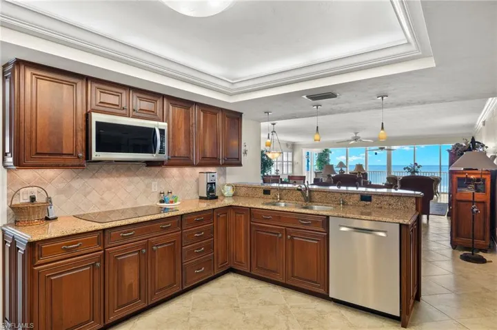 Kitchen featuring sink, kitchen peninsula, appliances with stainless steel finishes, decorative light fixtures, and ceiling fan
