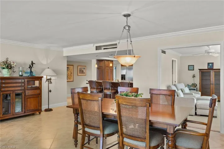 Tiled dining area featuring ceiling fan and ornamental molding