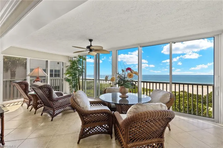 Sunroom with a water view, a beach view, ceiling fan, and plenty of natural light