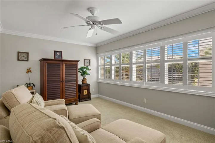 Living room featuring carpet floors, crown molding, and ceiling fan