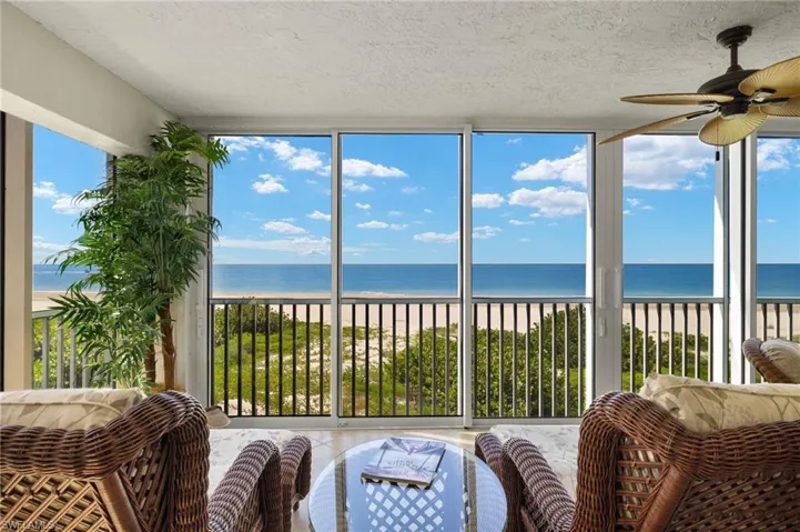 Sunroom featuring ceiling fan, a water view, and a wealth of natural light