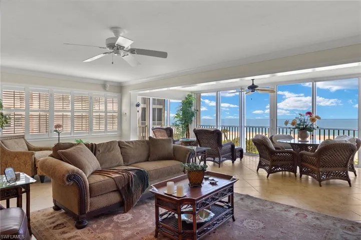 Living room with ornamental molding, a water view, ceiling fan, and tile patterned floors