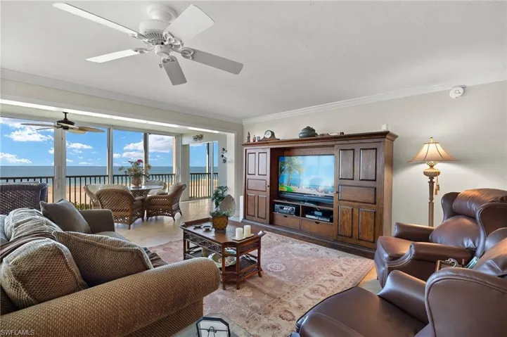 Living room featuring a water view, ornamental molding, and ceiling fan
