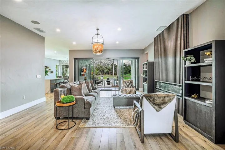 Living area with light wood-style floors, a chandelier, recessed lighting, and a fireplace