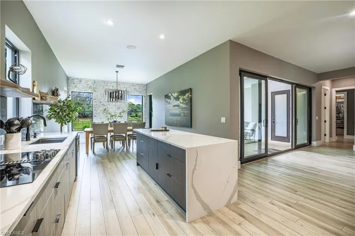 Kitchen featuring pendant lighting, modern cabinets, light stone countertops, black electric cooktop, and light wood-type flooring