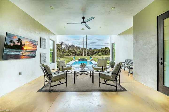 Fenced backyard featuring a ceiling fan, a patio, a pool with connected hot tub, and outdoor lounge area