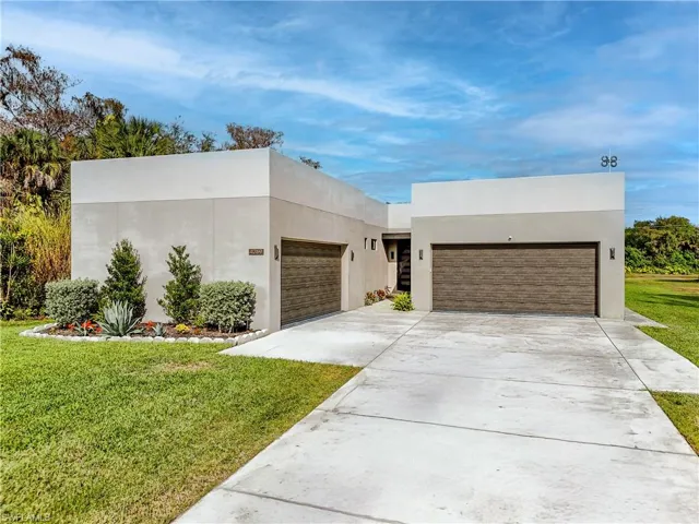 Contemporary house with stucco siding, a front yard, concrete driveway, and an attached garage