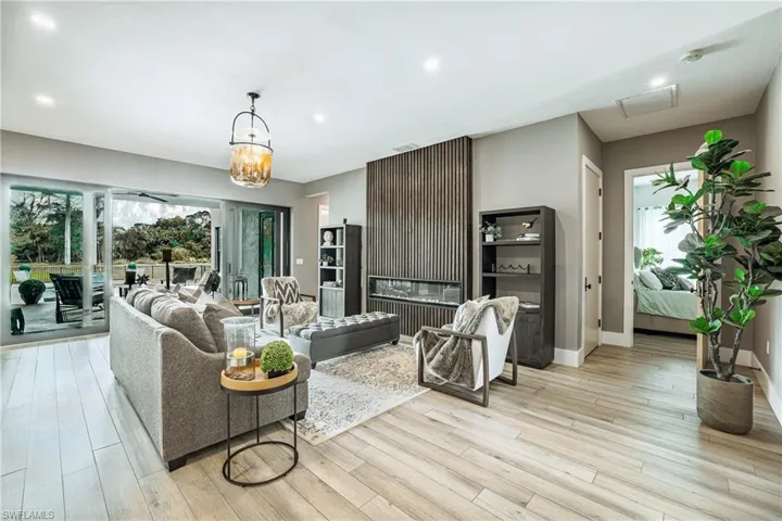 Living room with light wood finished floors, plenty of natural light, a chandelier, and recessed lighting