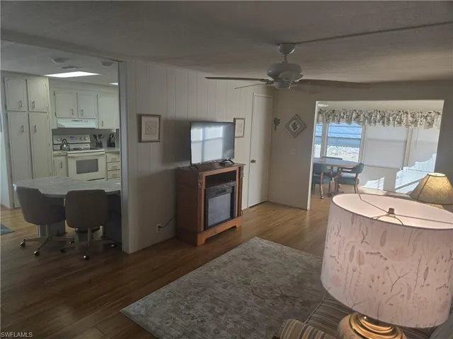 Living room with ceiling fan, dark hardwood / wood-style flooring, and a textured ceiling