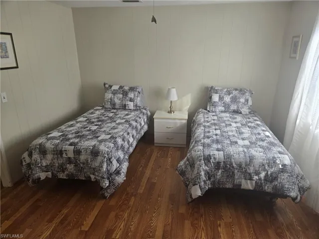 Bedroom with dark hardwood / wood-style floors and wood walls