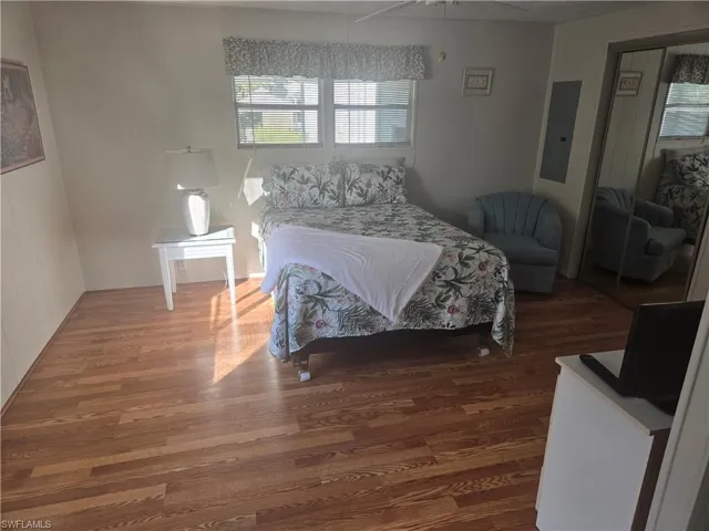 Bedroom with a closet, dark hardwood / wood-style floors, ceiling fan, and electric panel