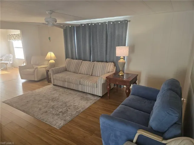 Living room with hardwood / wood-style flooring, ceiling fan, and wooden walls