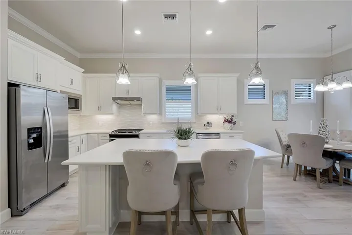 Kitchen featuring backsplash, crown molding, decorative light fixtures, and appliances with stainless steel finishes