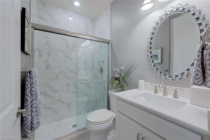 Bathroom featuring a shower with door, toilet, and vanity