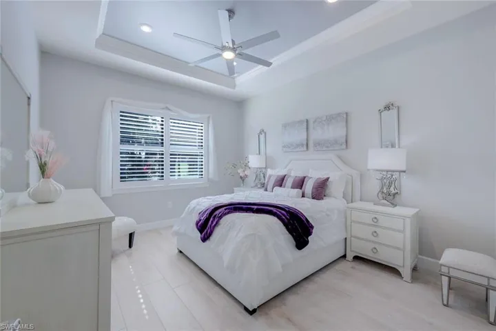 Bedroom with ceiling fan, light hardwood / wood-style flooring, and a raised ceiling