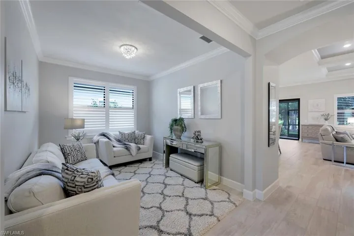 Living room featuring coffered ceiling, ornamental molding, light hardwood / wood-style floors, and beam ceiling