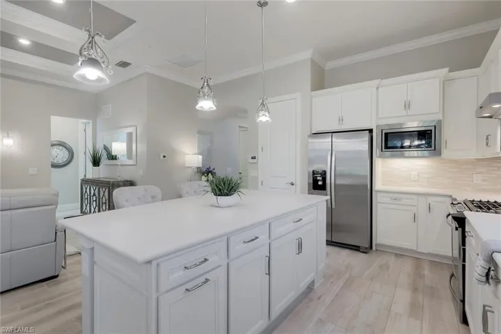 Kitchen featuring crown molding, light hardwood / wood-style flooring, stainless steel appliances, white cabinets, and backsplash