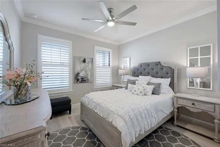 Bedroom with ceiling fan, crown molding, and wood-type flooring