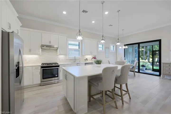 Kitchen featuring crown molding, stainless steel appliances, decorative light fixtures, backsplash, and a center island