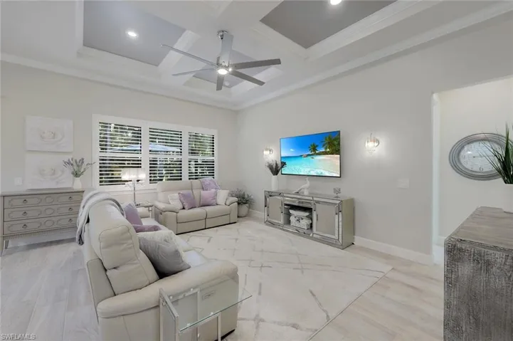 Living room with coffered ceiling, ceiling fan, light hardwood / wood-style floors, and crown molding