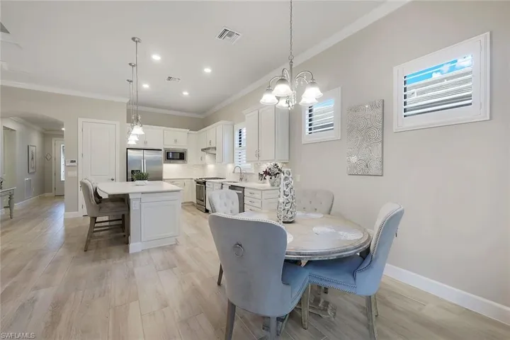 Dining space with a notable chandelier, sink, light hardwood / wood-style floors, and crown molding