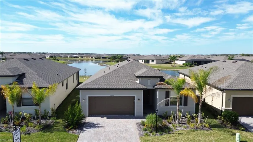 View of front of home featuring a residential view, decorative driveway, a water view, and an attached garage
