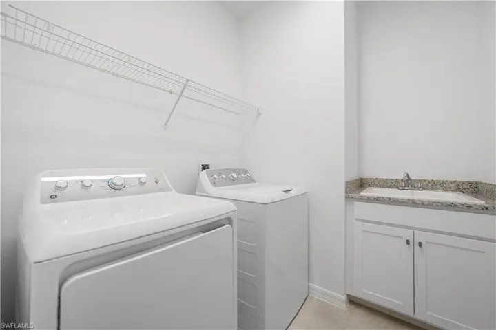 Laundry room with washing machine and dryer, cabinet space, and light tile patterned flooring
