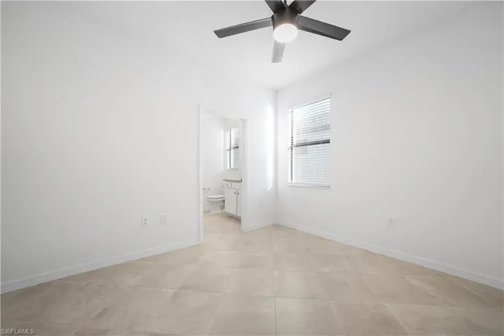 Unfurnished bedroom with a ceiling fan, connected bathroom, and light tile patterned floors