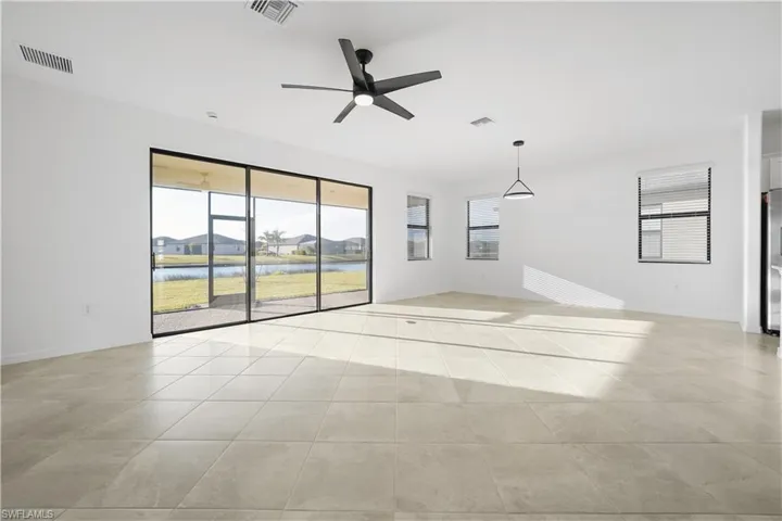 Unfurnished room featuring ceiling fan, healthy amount of natural light, a water view, and light tile patterned floors