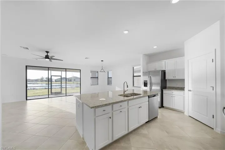 Kitchen featuring white cabinets, plenty of natural light, light stone countertops, a ceiling fan, and recessed lighting