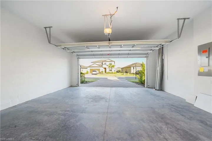 Garage featuring electric panel, concrete block wall, and a residential view