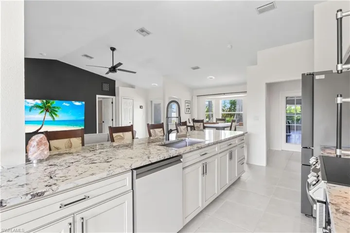 Kitchen featuring dishwasher, vaulted ceiling, ceiling fan, stainless steel range oven, and light stone counters