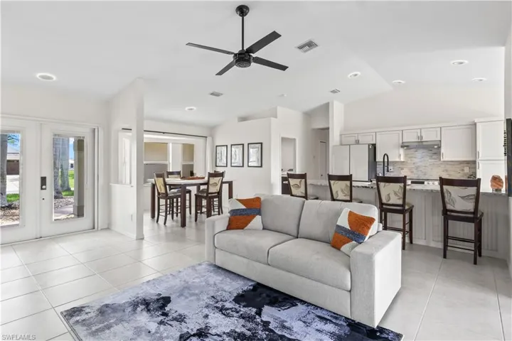Living room with light tile patterned flooring, lofted ceiling, ceiling fan, and french doors